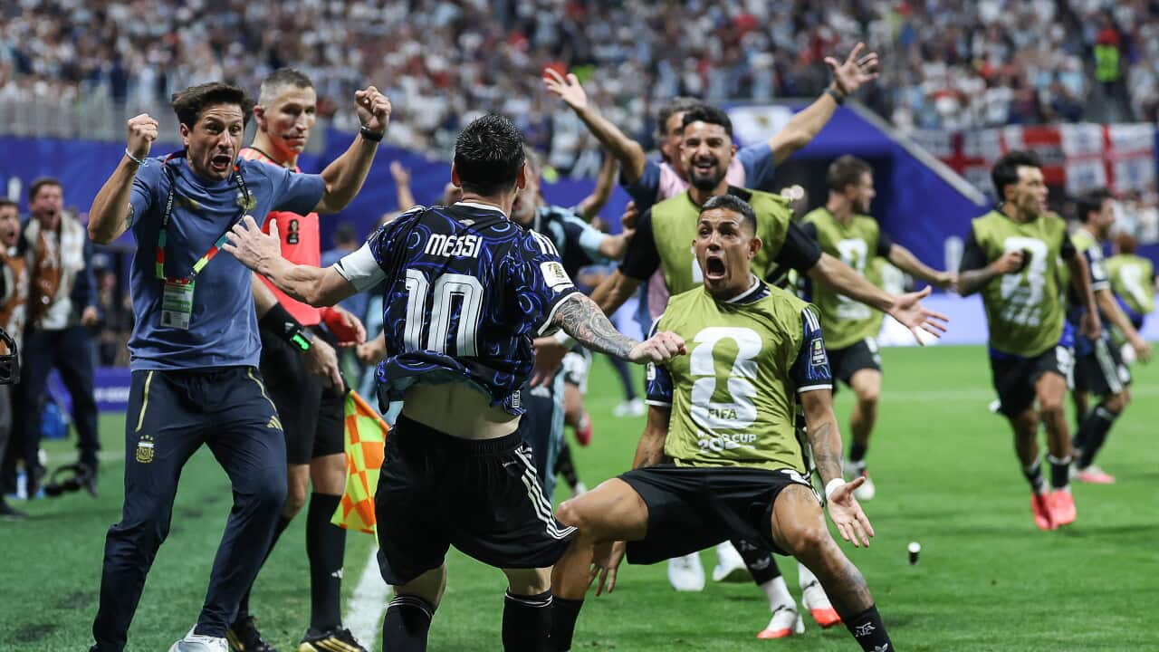 A group of football players from Argentina's team, wearing blue jerseys, celebrate together on the field.