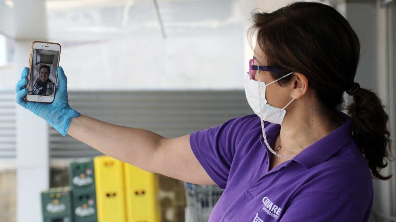 A woman wearing a face mask and gloves makes a video call with her niece while remaining in social isolation in Nicosia, Cyprus