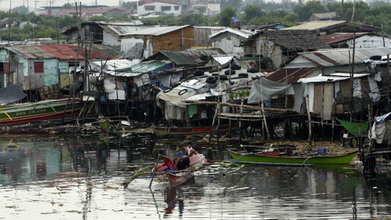 Filipinos on a makeshift boat paddle on the swelling river