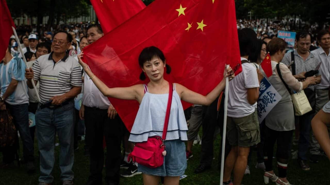 A woman embraces a Chinese flag during pro-government Safeguard Hong Kong rally at Tamar Park