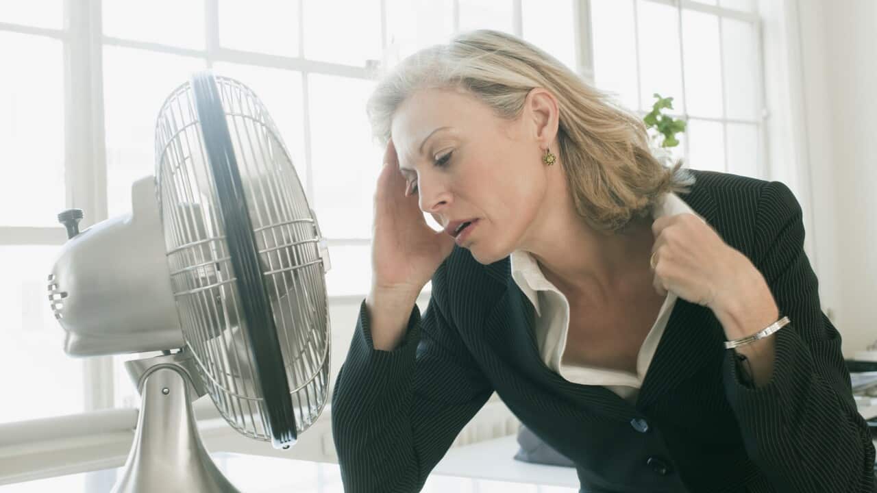 Hot businesswoman sitting in front of fan