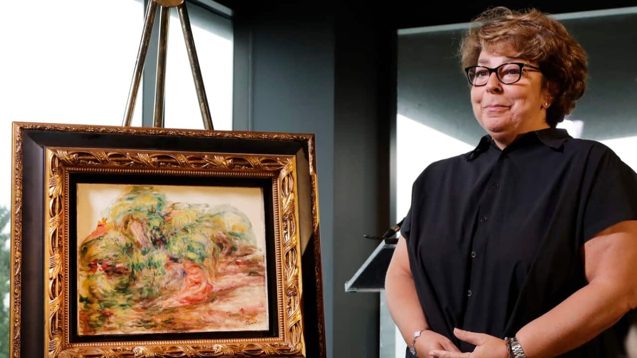 Sylvie Sulitzer, a delicatessen owner from the south of France, stands with a Renoir painting that was returned to her in a reparation ceremony at a news conference