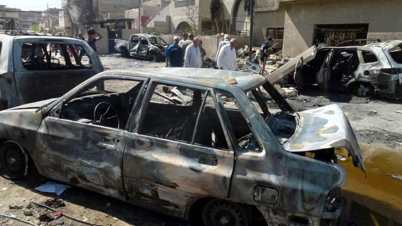 Iraqis inspect the damage at the site of a bombing attack