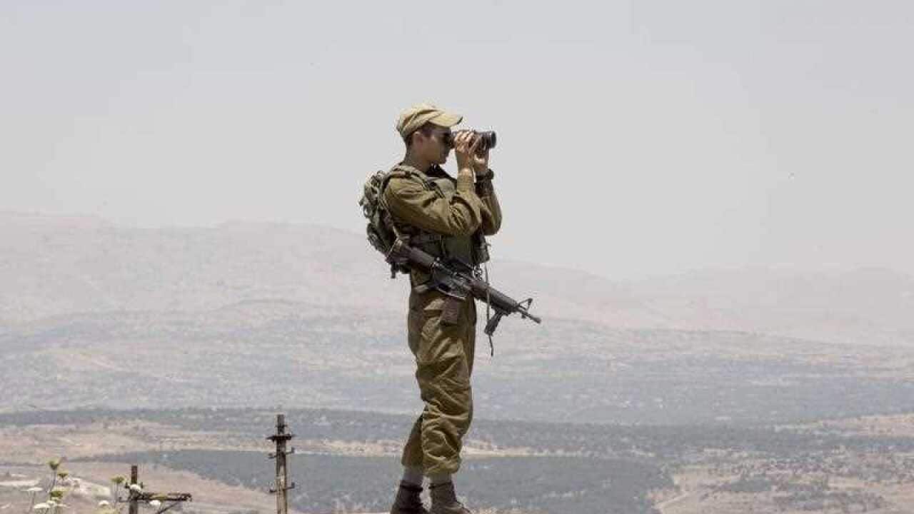 An Israeli soldier observes smoke rising from Syrian village as a result of fighting near the city of Quneitra, in the Golan Heights, as seen from the Israeli side of the border, 26 June 2017.