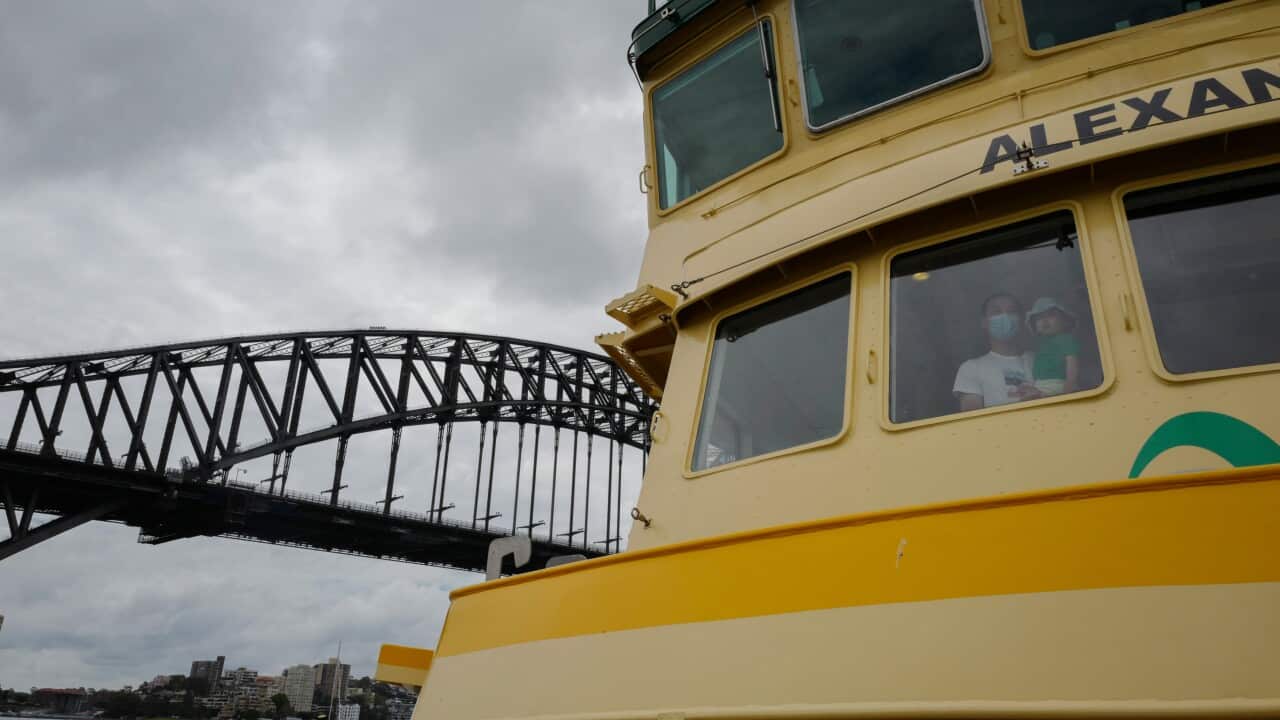 A man wearing a face mask holds a child inside a Sydney Ferry