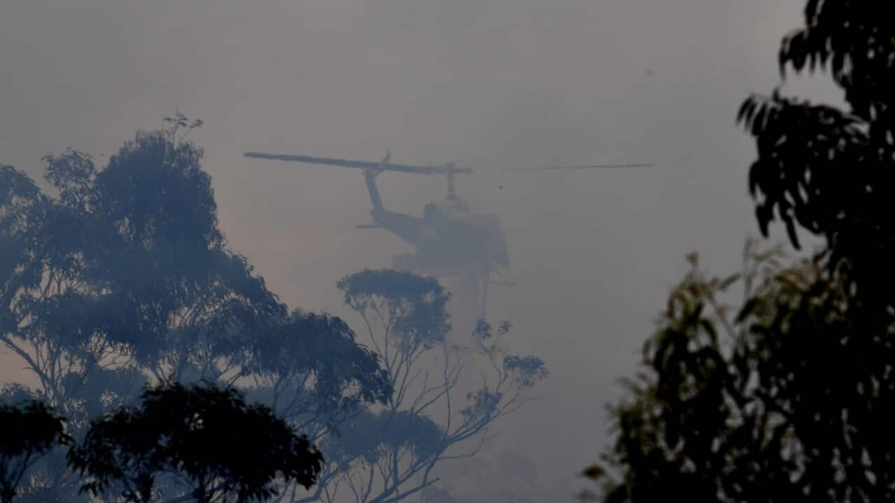 A water bombing helicopter helps to contain the Gospers Mountain Fire