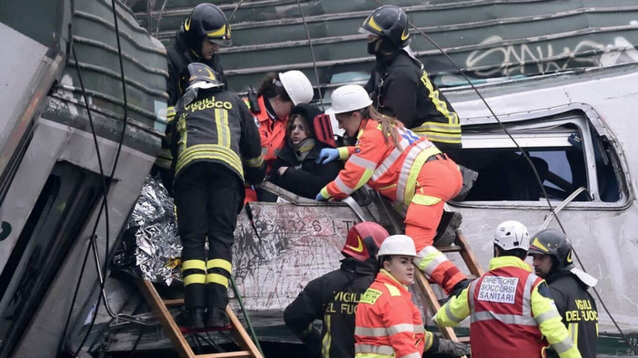Rescuers help people after a derailed train near Milan