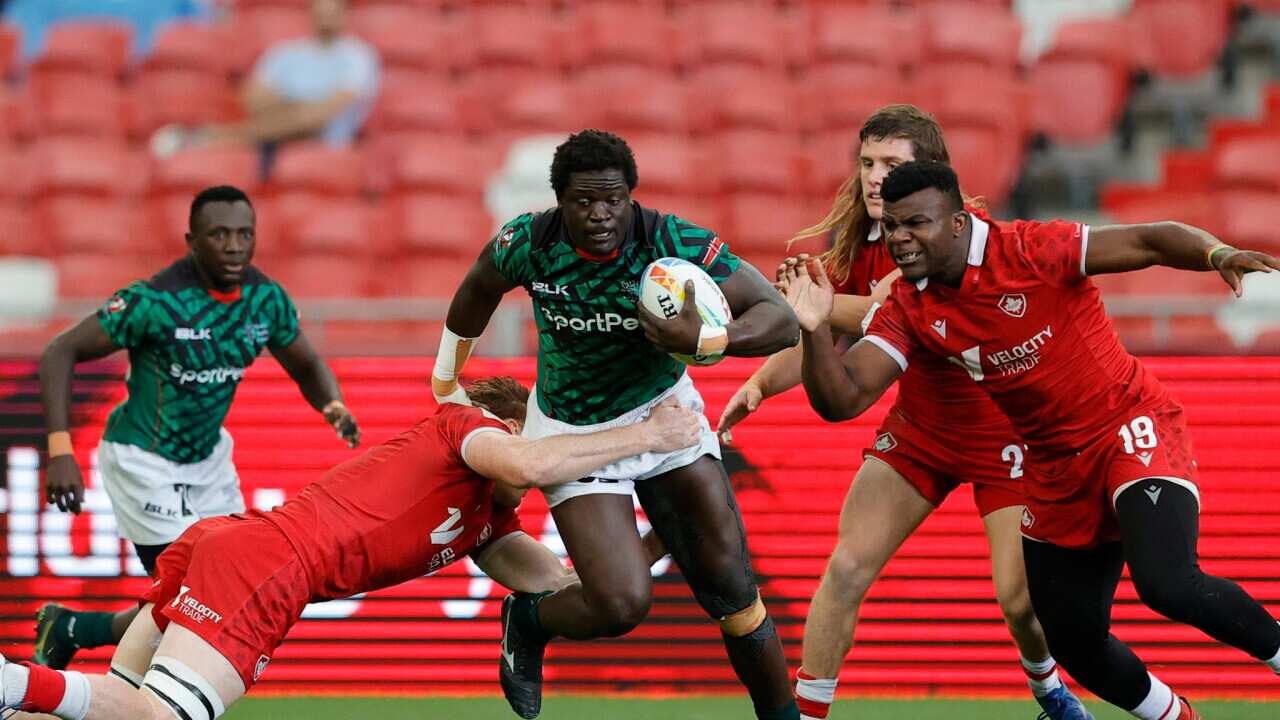 Nyota wa Kenya akabwa na wachezaji wa Canada katika mechi ya mchujo mjini London..jpg