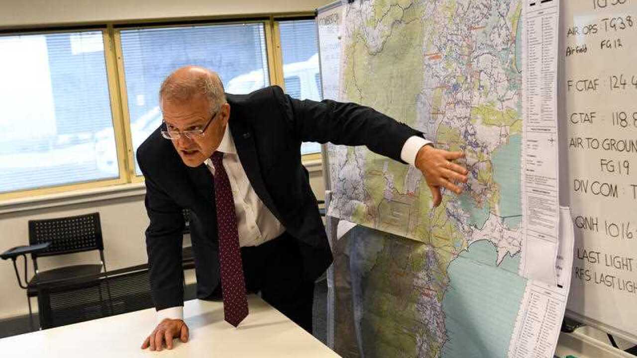 Prime Minister Scott Morrison takes a look at a map of an area impacted by bushfire during an operational update in Nowra, Sunday 5 January, 2020