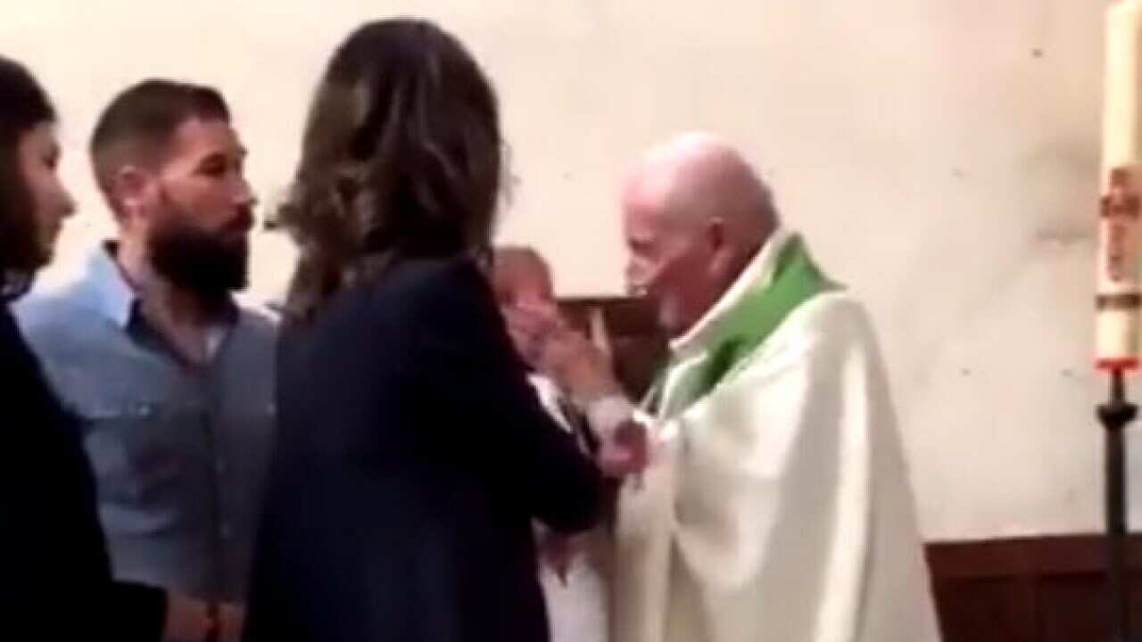 The family shocked when the priest slaps the baby across the face.
