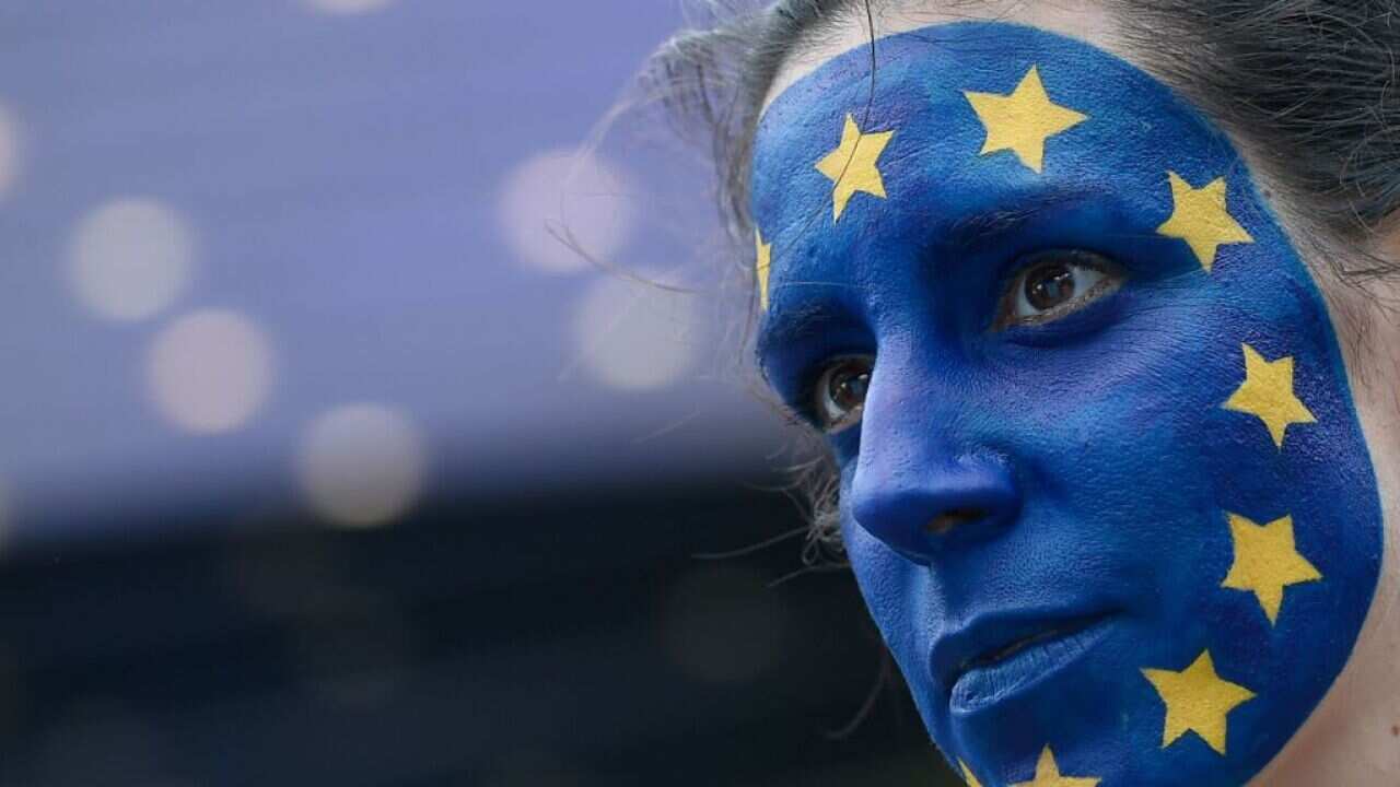 A woman with an European flag painted on his face stands outside the European Parliament in Brussels.