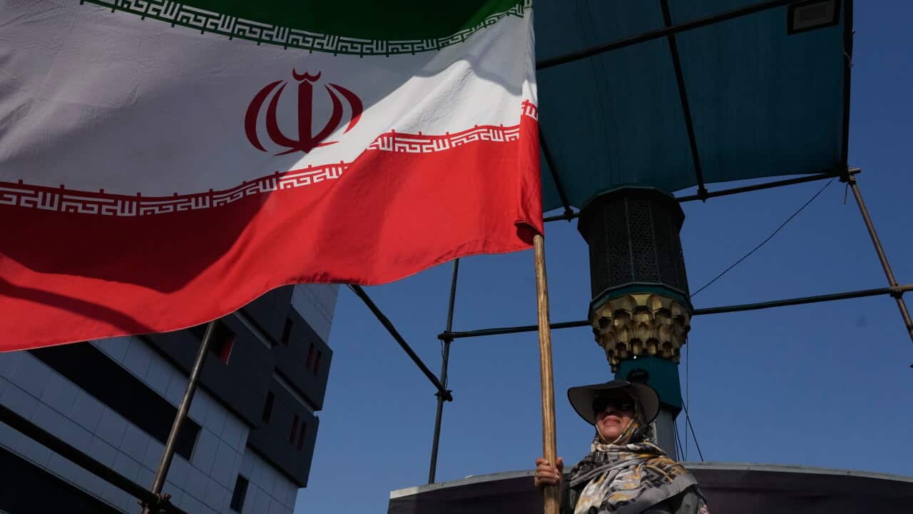 A woman holds up a green, white and red flag