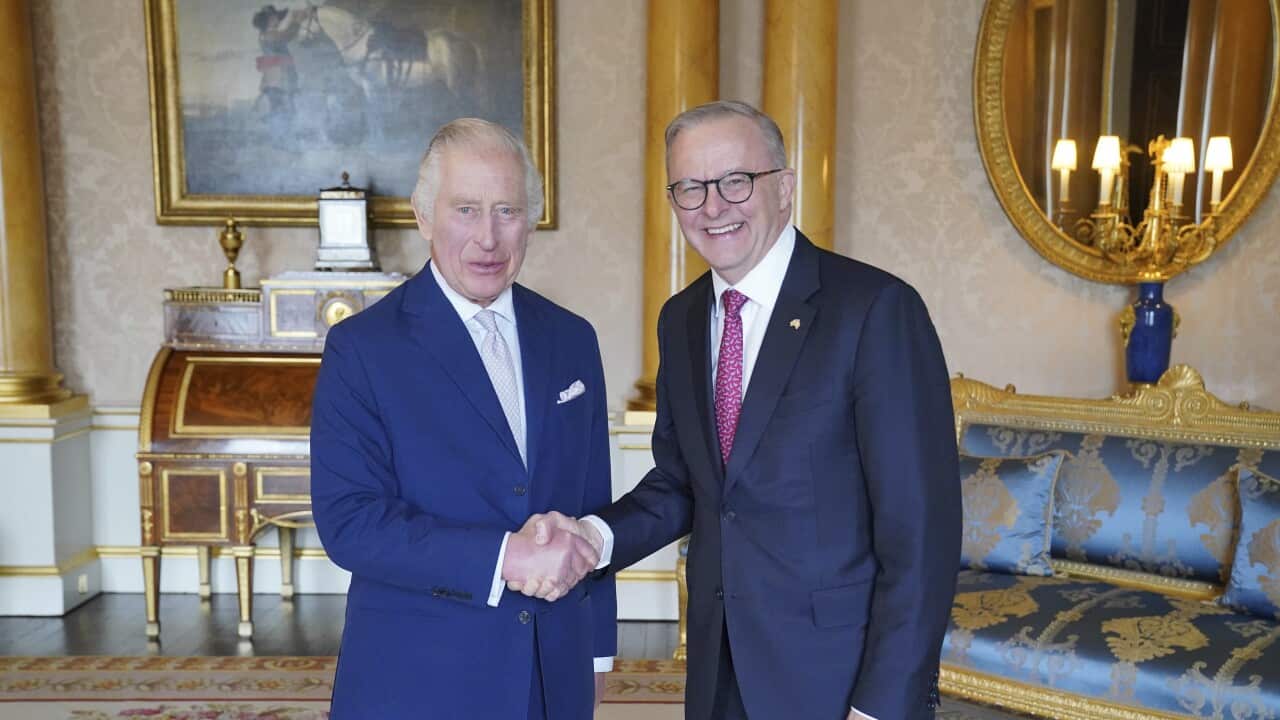 Two men wearing suits and ties are shaking hands.