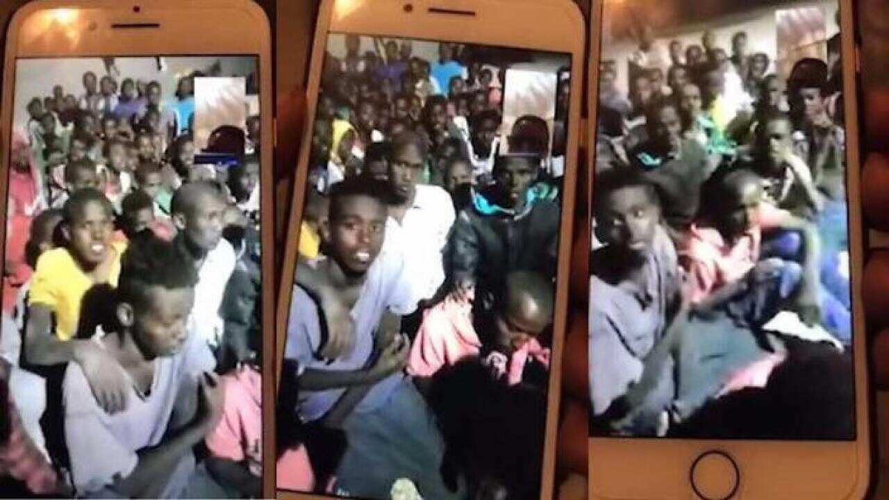 Images from a Facebook video showing Somali and Ethiopian migrants huddled in a concrete room suffering abuse at the hands of Libyan gangs.