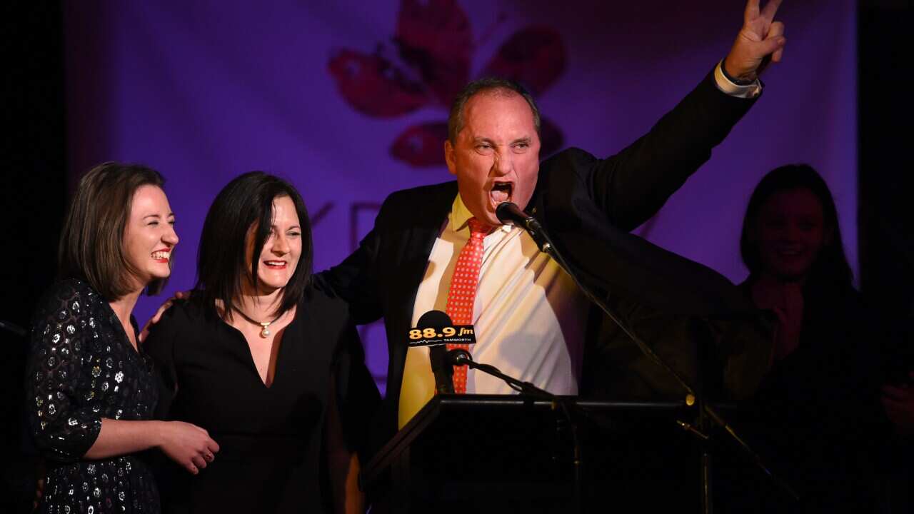 Deputy Prime Minister and leader of the National Party Barnaby Joyce, alng with his wife Natalie (left), and daughters, gestures as he claims victory for the seat of New England