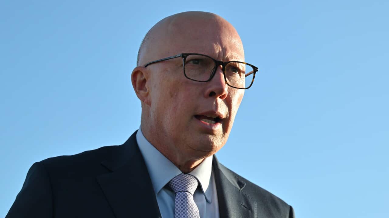 Peter Dutton standing in front of a bright blue sky.