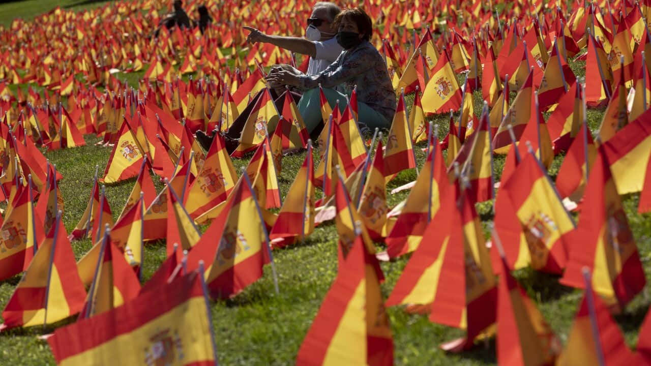 People sit among the Spanish flags placed in memory of coronavirus (COVID-19) victims in Madrid, Spain.