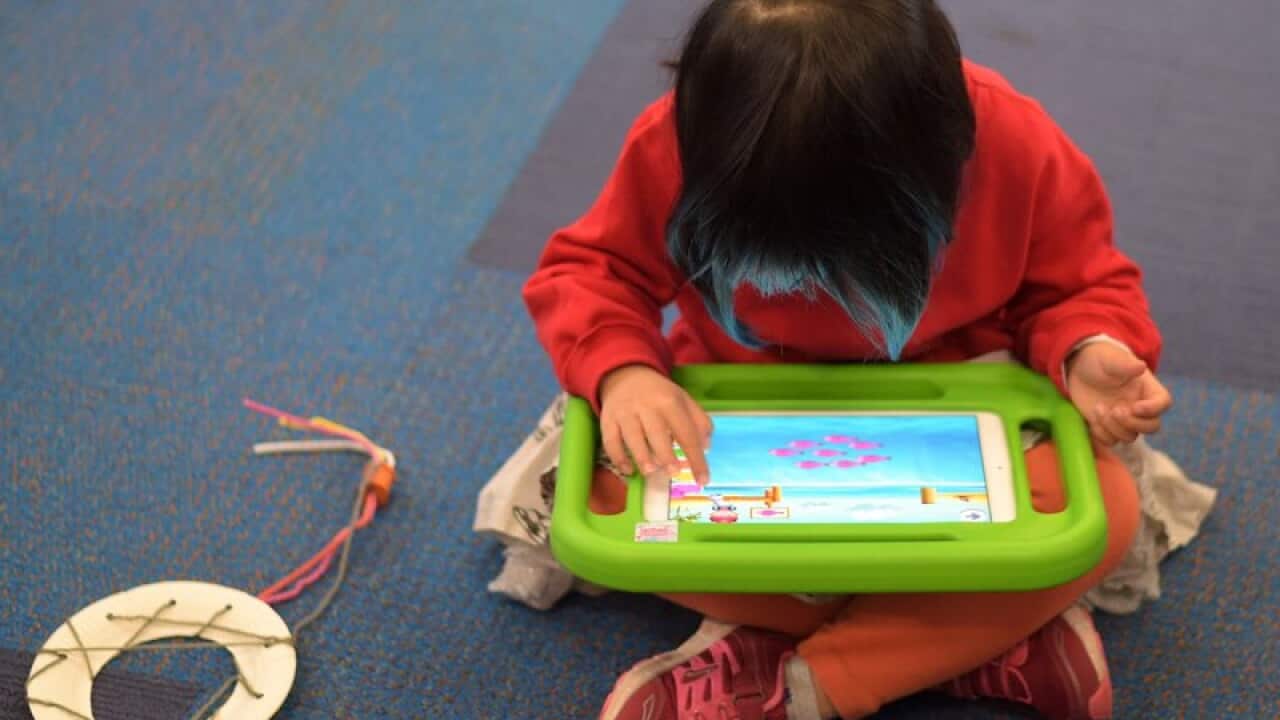 A girl plays on an iPad at an early learning school