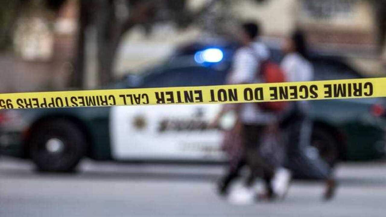 A group of persons walk in front of a Broward County sheriff car after a shooting at Marjory Stoneman Douglas High School in Parkland.
