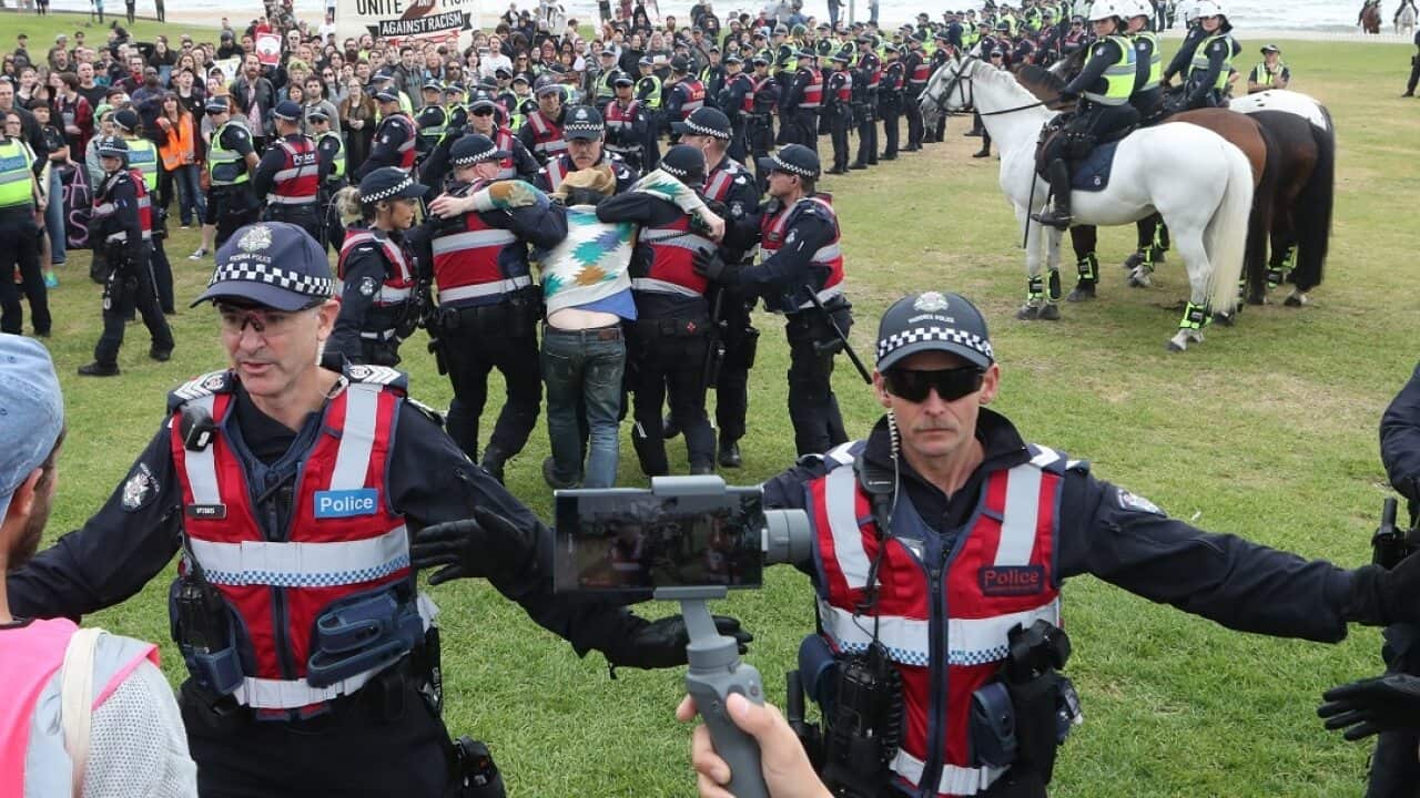 Police keep protesters apart as a man is arrested on the St Kilda foreshore in Melbourne.
