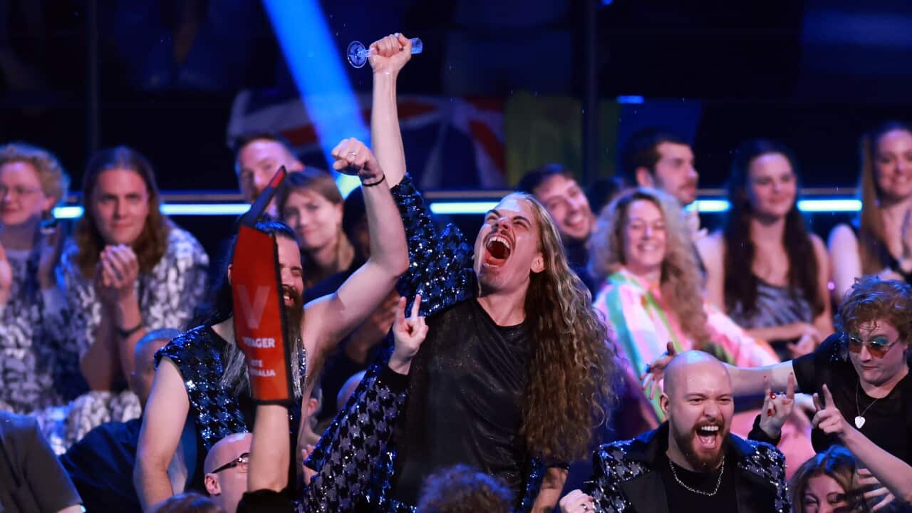 A man surrounded by a crowd raises his fist in the air in celebration.
