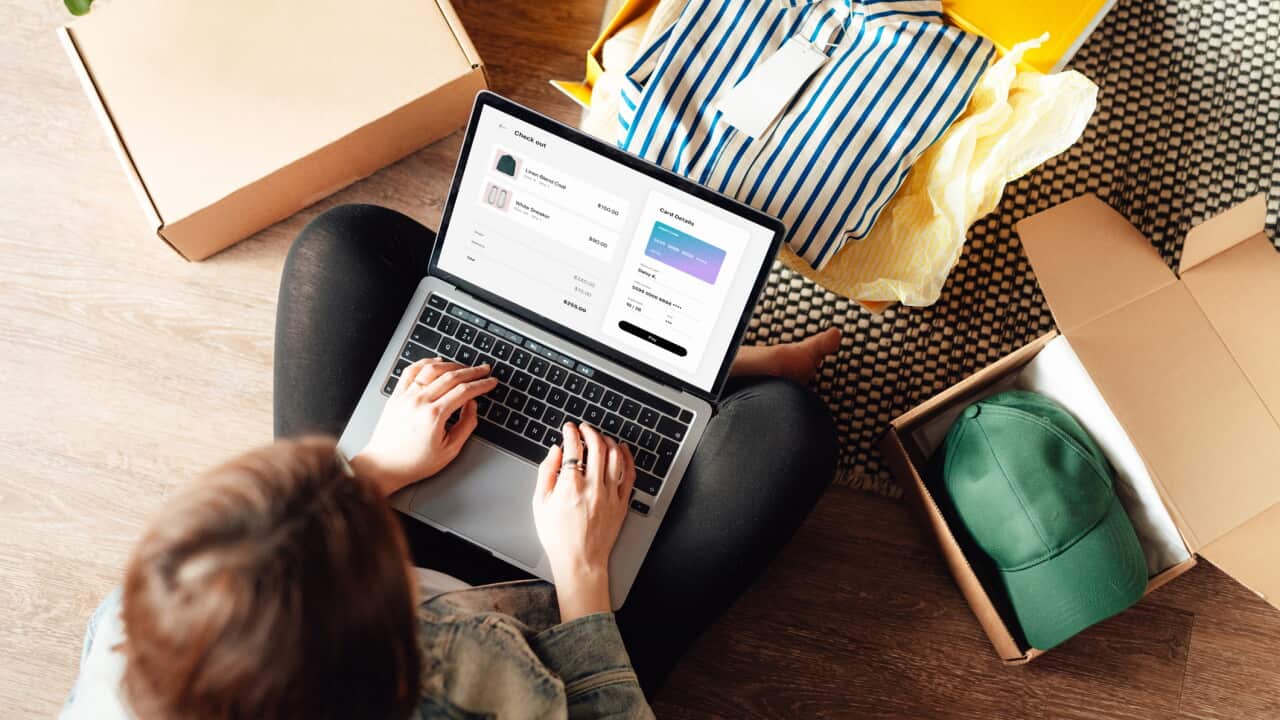 Young woman doing online shopping with laptop sitting on the floor at home