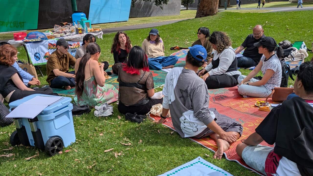 Participants of the 'Barang-Bareng' event sit on mats at Carlton Gardens, sharing stories about their identity through meaningful objects from Indonesia. Credit_ SBS Indonesian_Anne Parisianne.jpg
