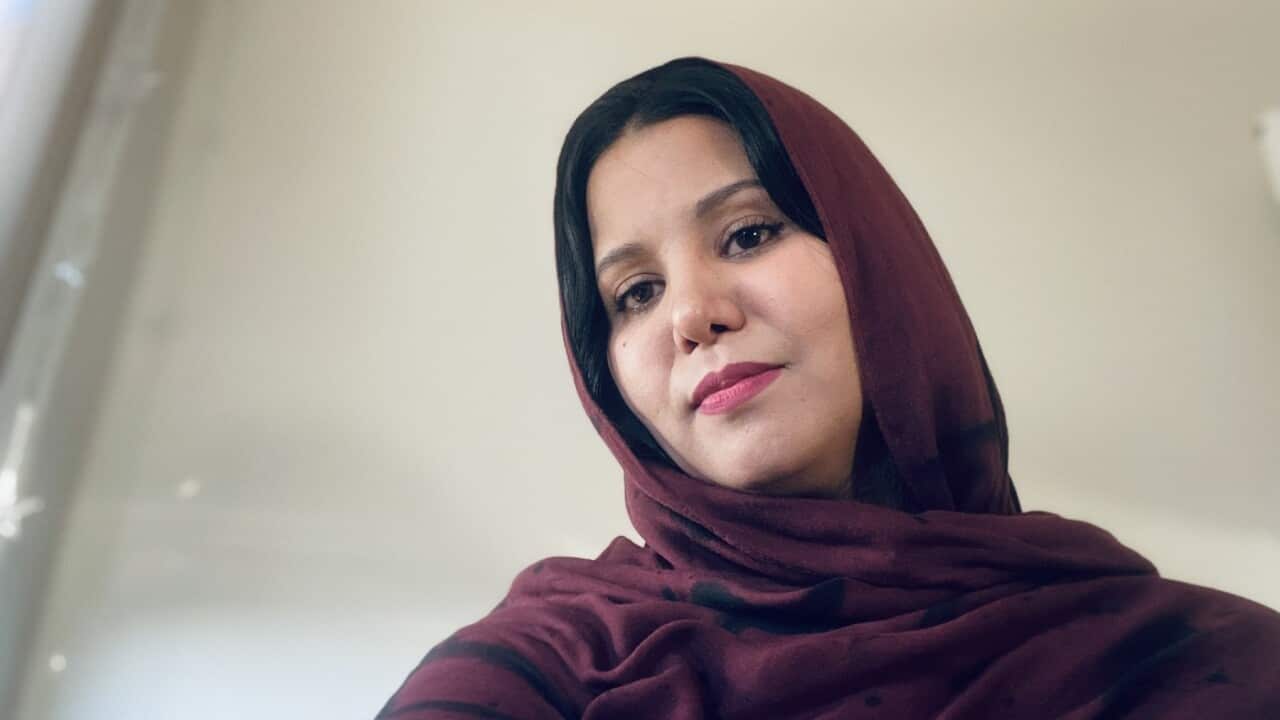 A woman with black hair wearing a deep purple headscarf