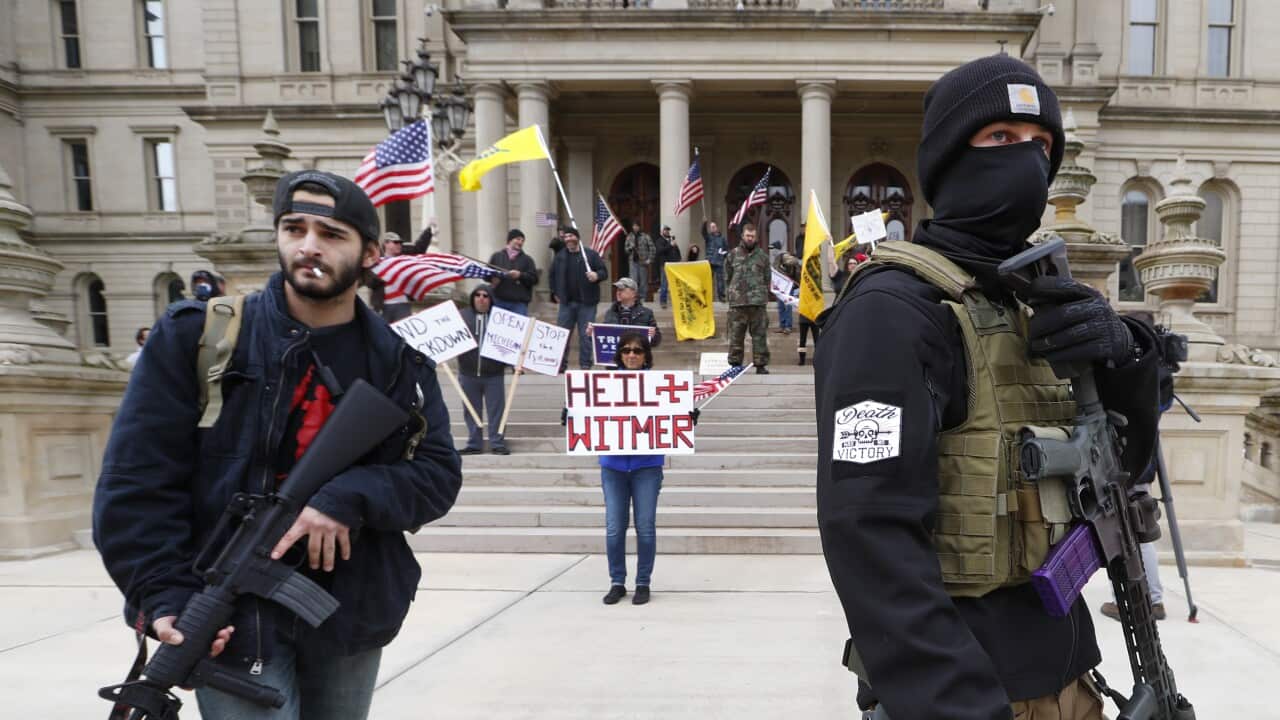 Protesters carry rifles near the steps of the Michigan State Capitol building in Lansing, Michigan.