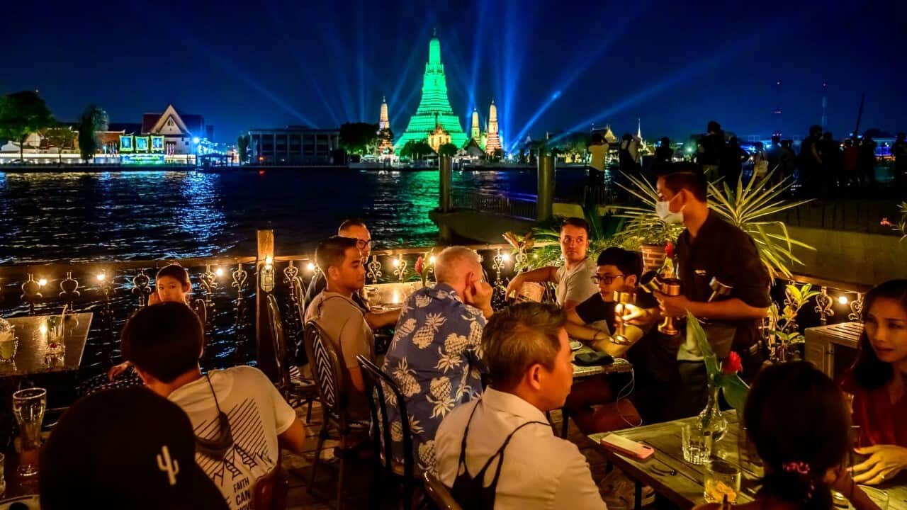People dine on a restaurant terrace in front of the stupa of the Buddhist temple Wat Arun (MLADEN ANTONOV - AFP via Getty Images)