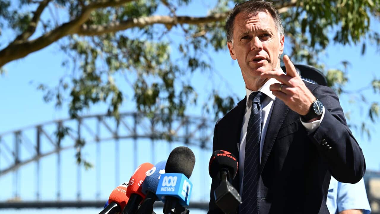 A middle-aged white man speaking a press conference, a bridge can be seen in the background