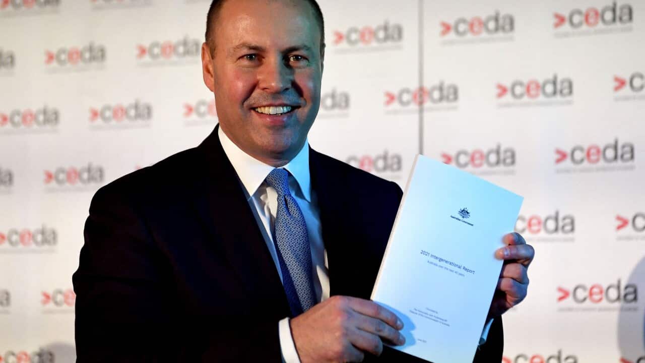 Australian treasurer Josh Frydenberg holds a copy of the 2021 Intergenerational Report in Melbourne on June 28, 2021.