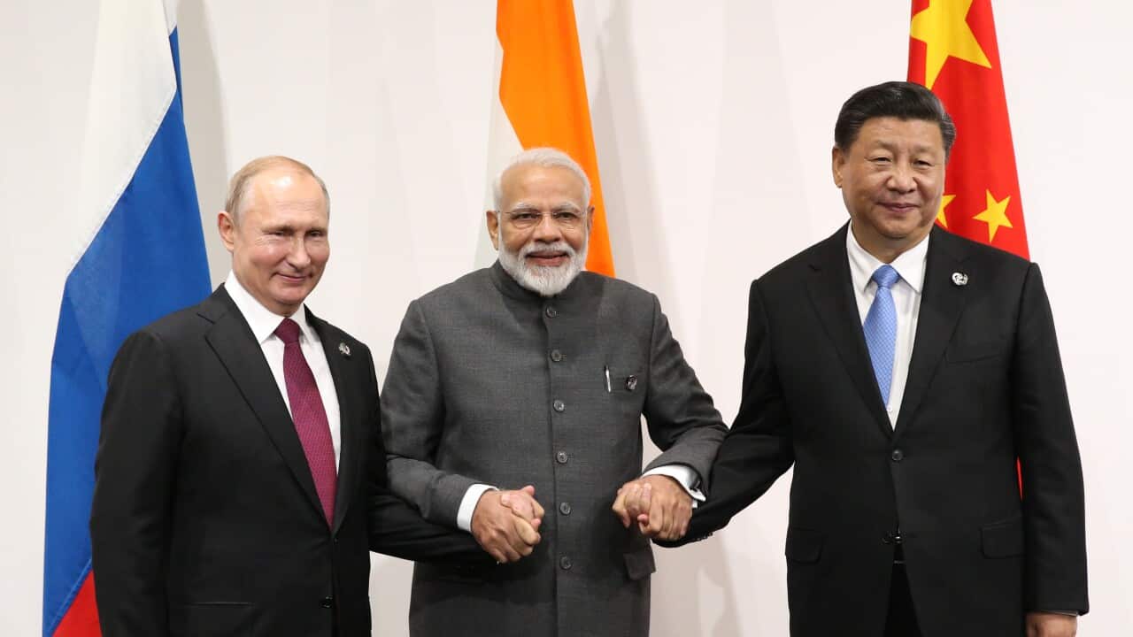 (l-r) Russian President Vladimir Putin, Indian Prime Minister Narendra Modi and Chinese President Xi Jinping stand in front of their countries' flags.