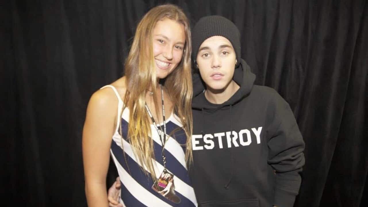 A young girl standing next to Justin Bieber