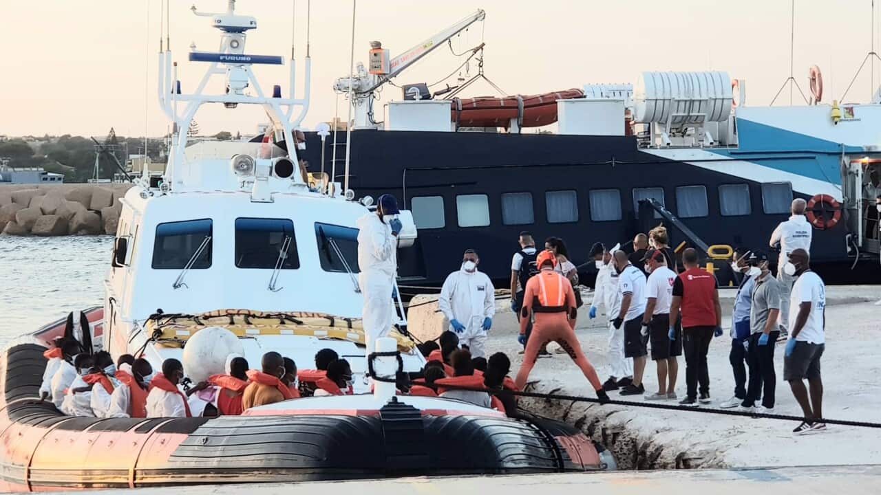 Migrants disembark from a boat that transhipped 49 migrants rescued by the Louise Michel ship, founded by British artist Banksy.