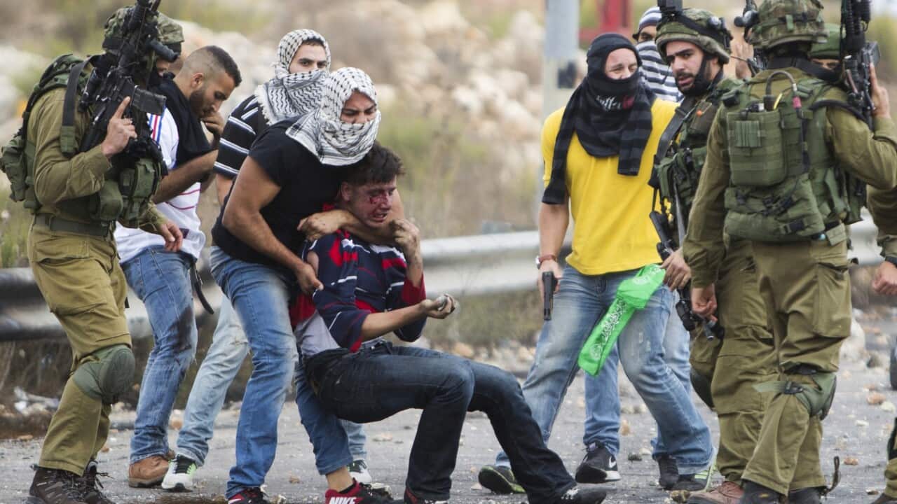 Undercover Israeli police officers and Israeli soldiers detain a wounded Palestinian demonstrator. (AP)