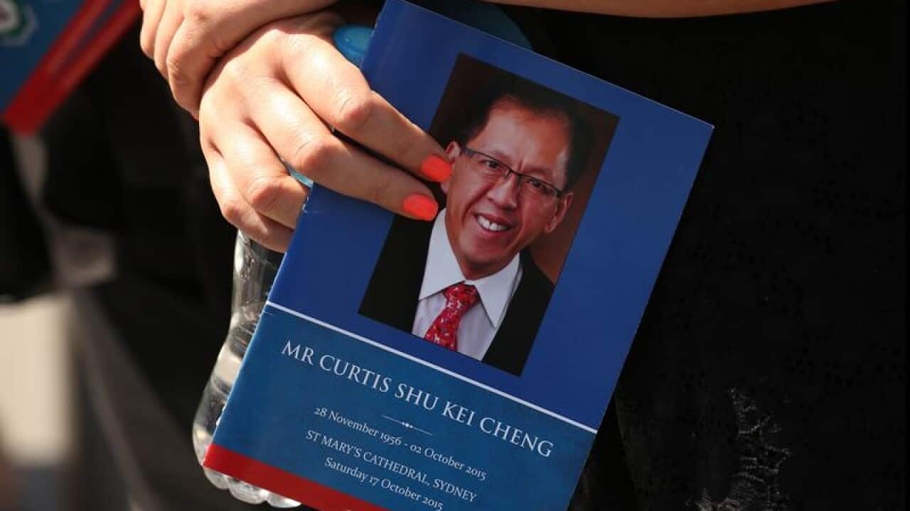 A woman holds an order of funeral service for Curtis Cheng