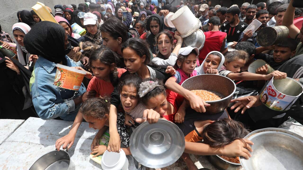 A large group of children, some holding buckets.