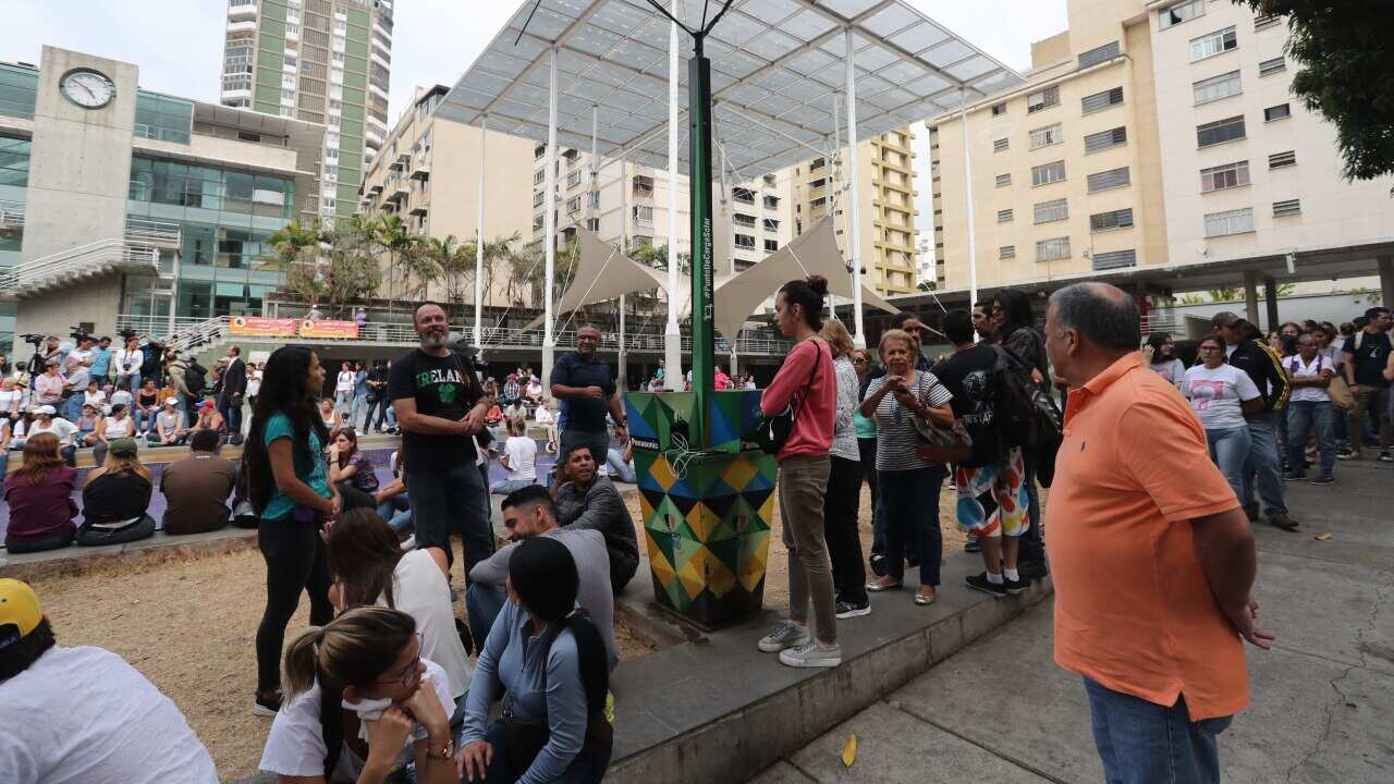 A group of people wait for recharging the battery of their cell phones in a public point, during a power outage in Caracas, Venezuela.
