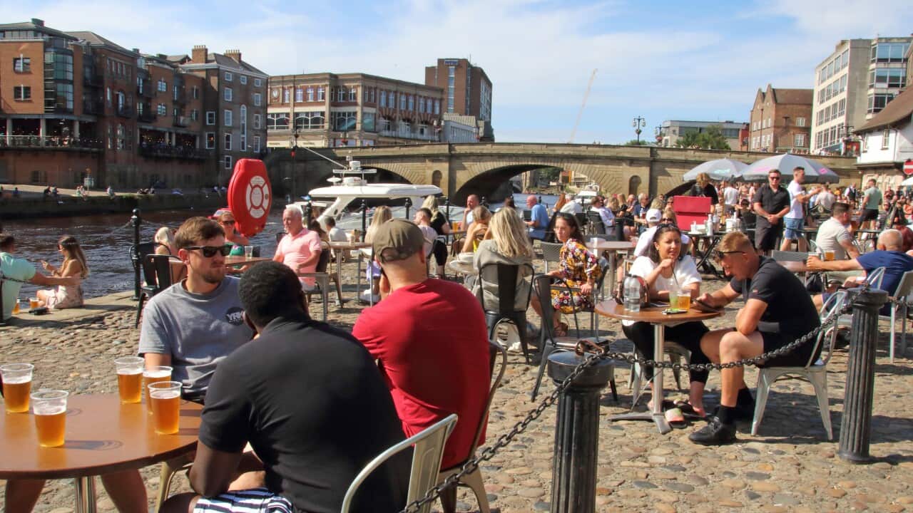 Crowds of people sit outside pubs and bars in Yorkshire, England.