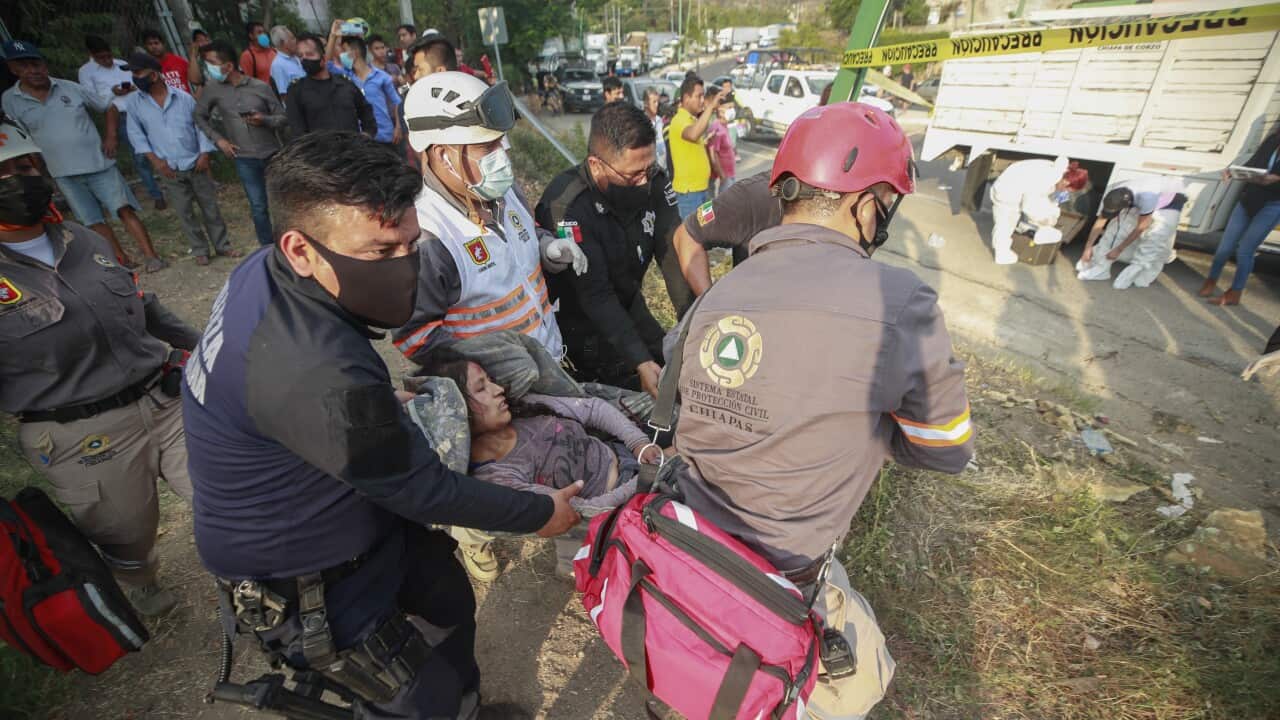 An injured migrant woman is moved by rescue personnel from the site of the accident