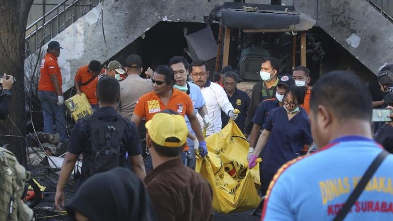 Officers carry a body bag out of one of the bomb sites
