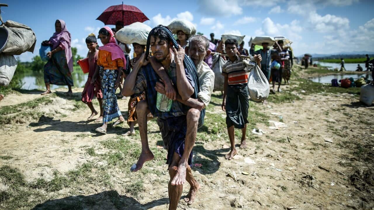 A Rohingya refugee carries his father at the Myanmar-Bangladesh border.