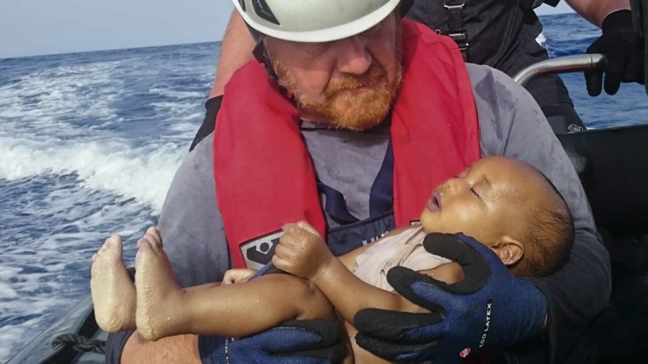 A crew members holds a drowned migrant baby during a rescue operation