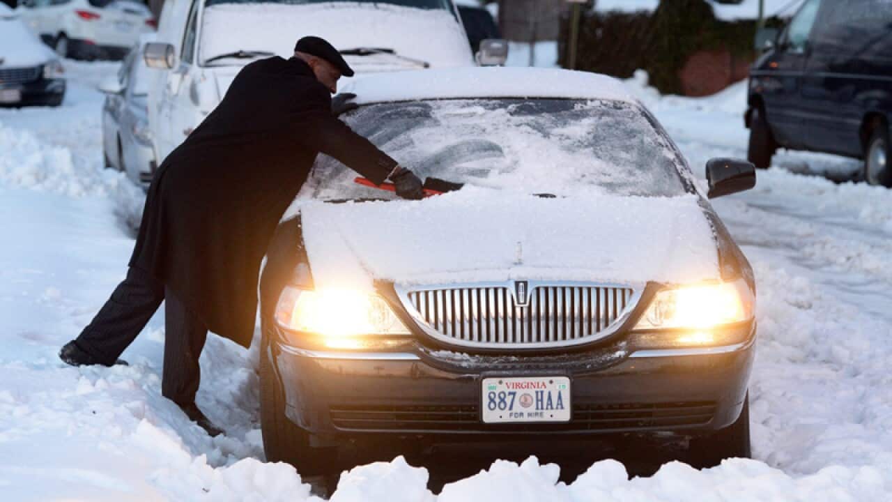 A man works to free his car from snow.
