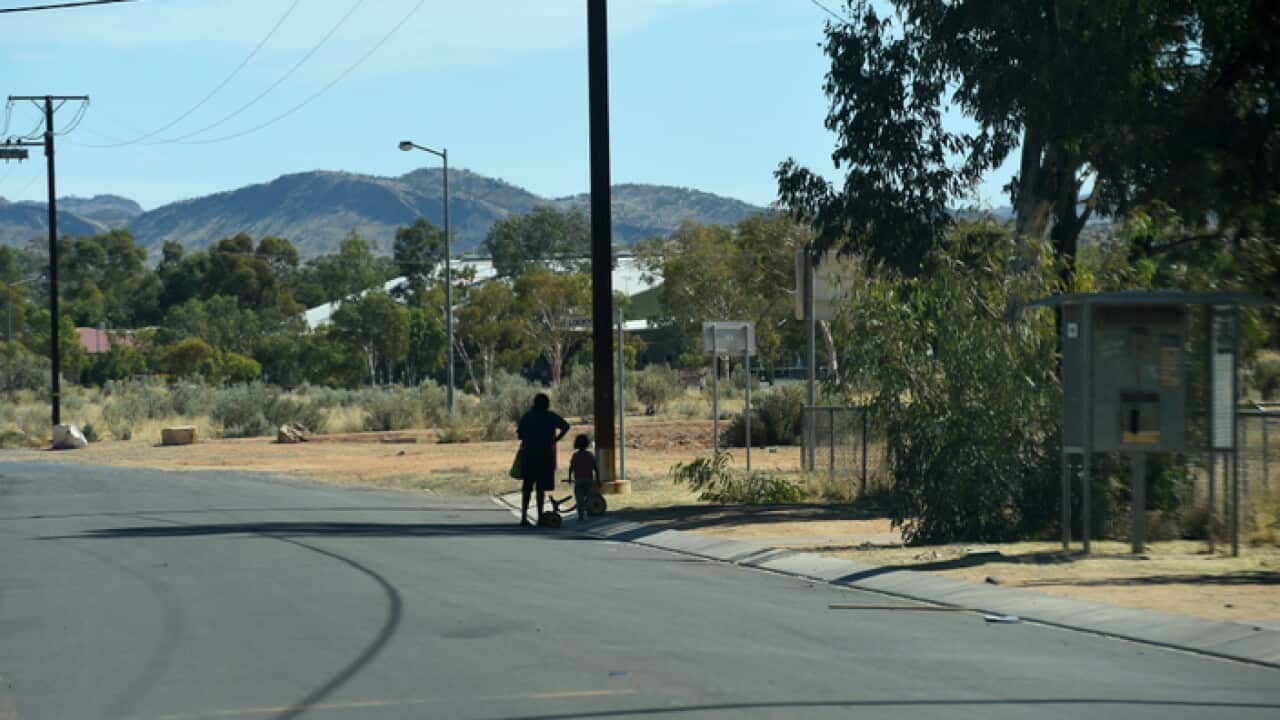 A woman and child wait for a ride at the Hidden Valley town camp near Alice Springs, Wednesday, May 27, 2015. (AAP Image/Dan Peled) NO ARCHIVING