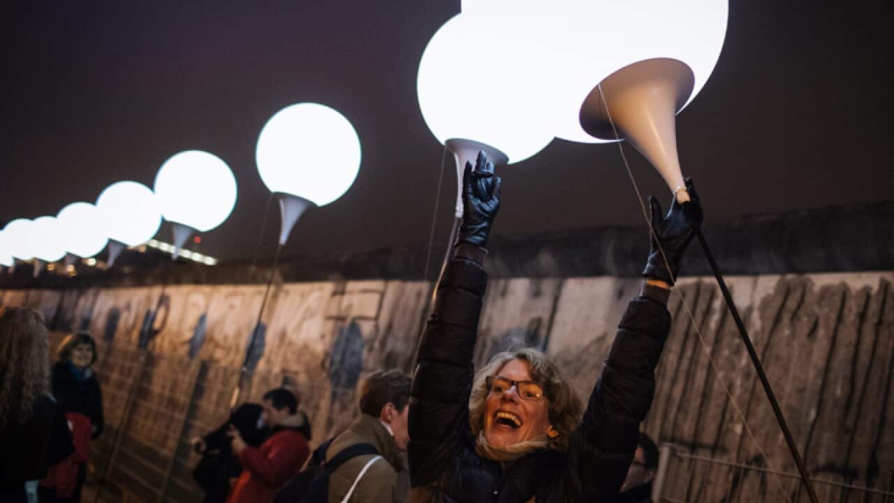 A woman holds a balloon at the Berlin Wall Anniversary.