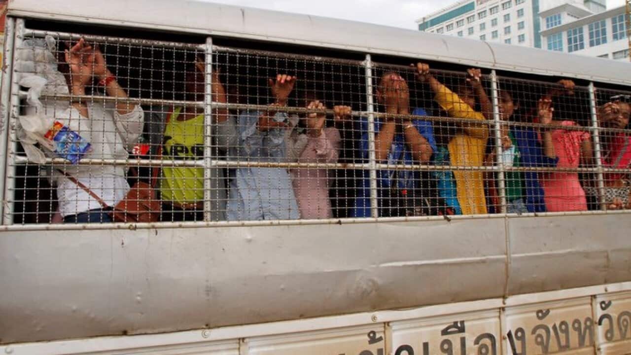 Cambodian migrant workers stand in a Thai police truck