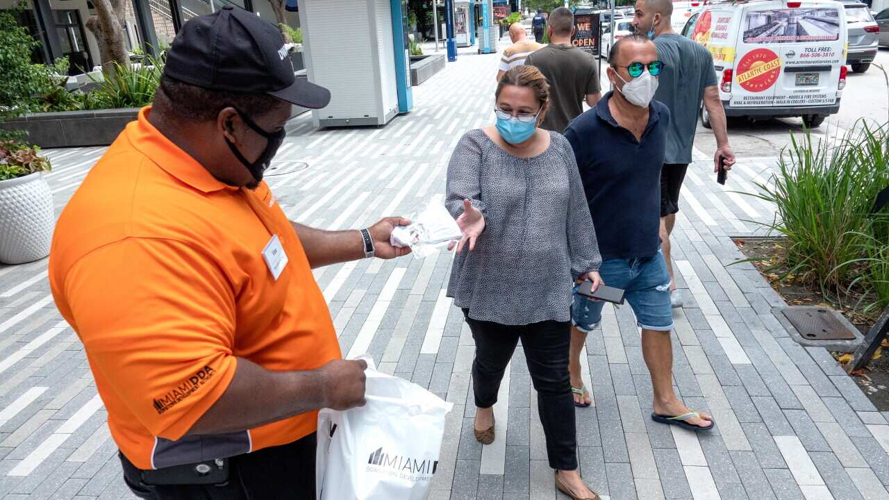 An health worker distributes free face masks in Downtown Miami, Florida.