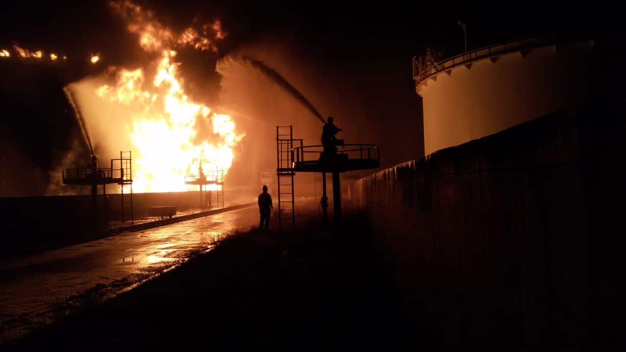 Libyan firefighters dousing a huge blaze at an oil tank started by clashes around Tripoli airport on July 28, 2014 in southern Tripoli. (AAP)